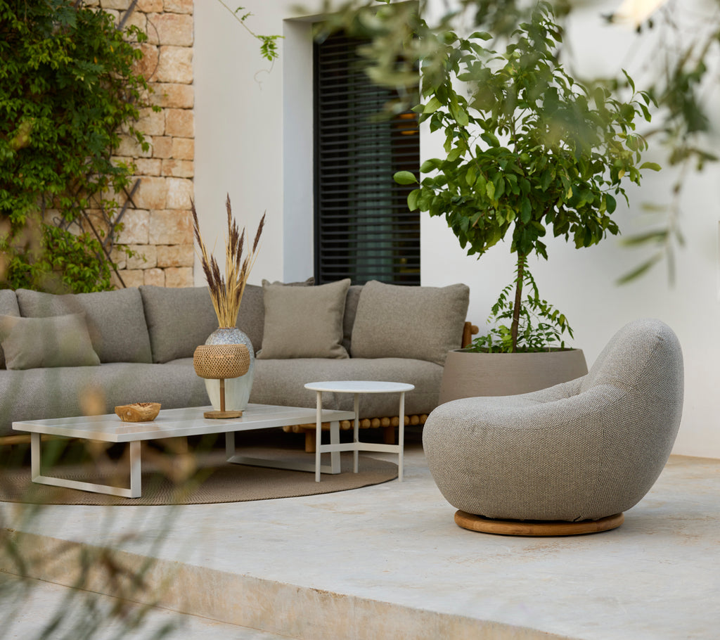 Moderne loungeområde med en grå seksjonssofa, hvit kaffebord og rund stol.