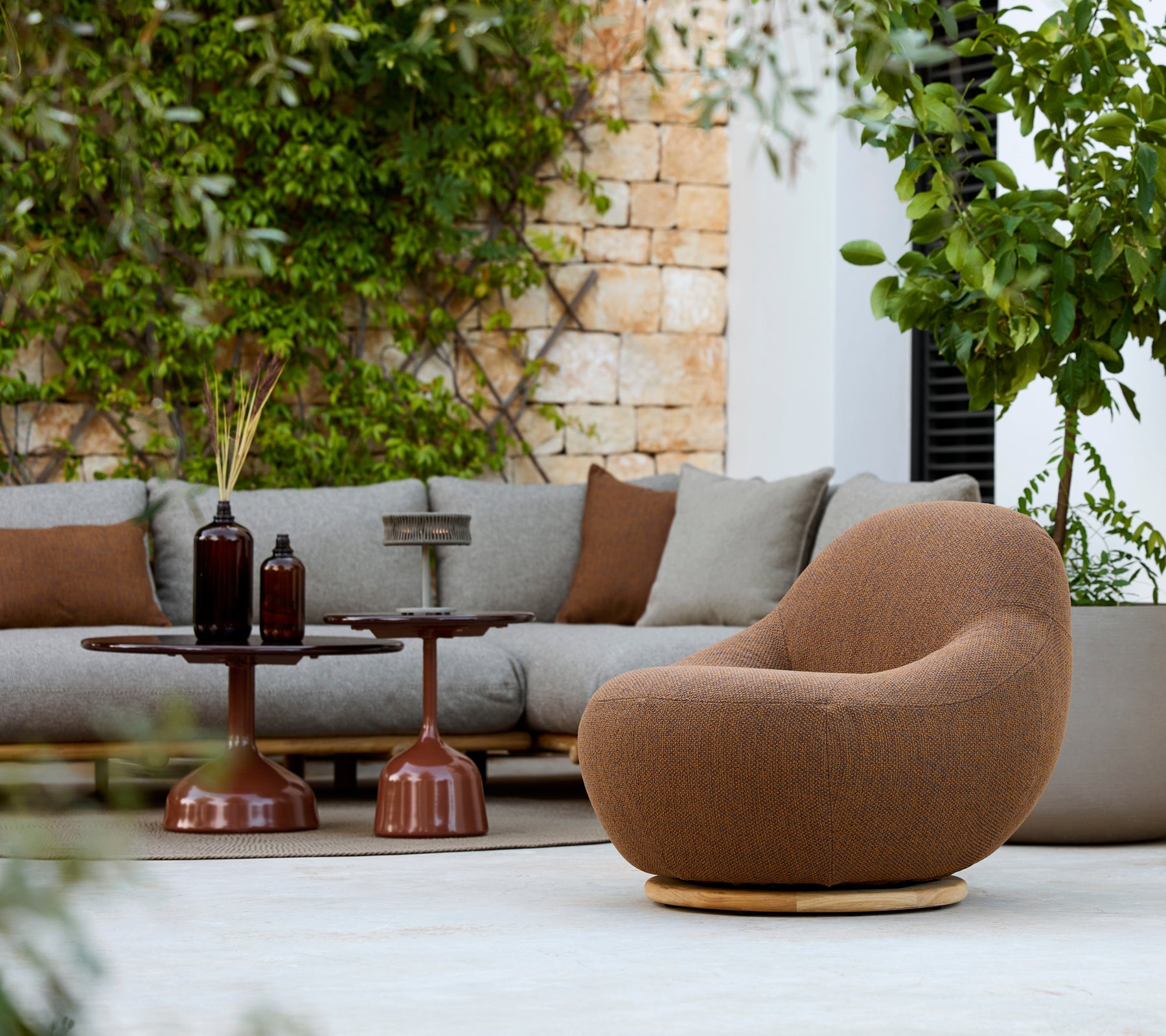 Moderne loungeområde med en brun lenestol, grå sofa og brun sidebord.
