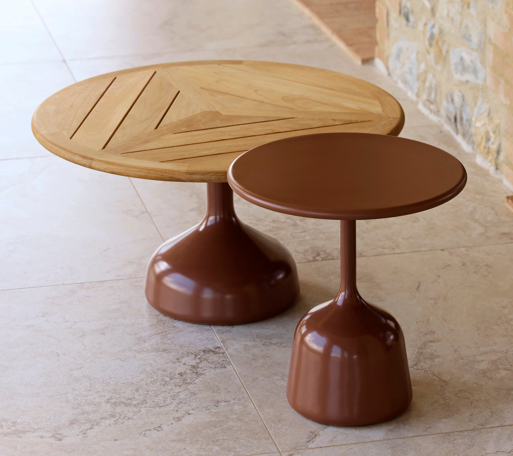 Two coffee tables, one with a wooden top and geometric design, the other with a smooth, desert red finish, sharing a modern aesthetic.