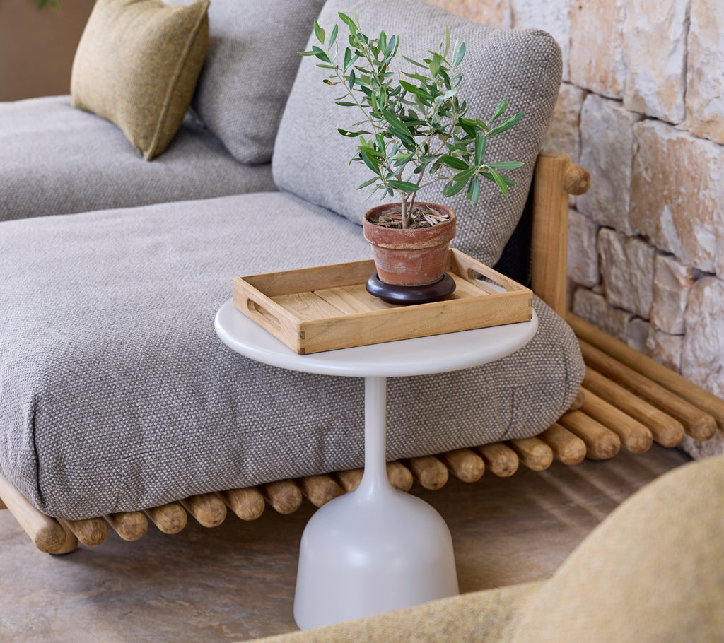 Moderne stueoppsett med en grå sofa, et hvitt sidebord og en grønn plante.