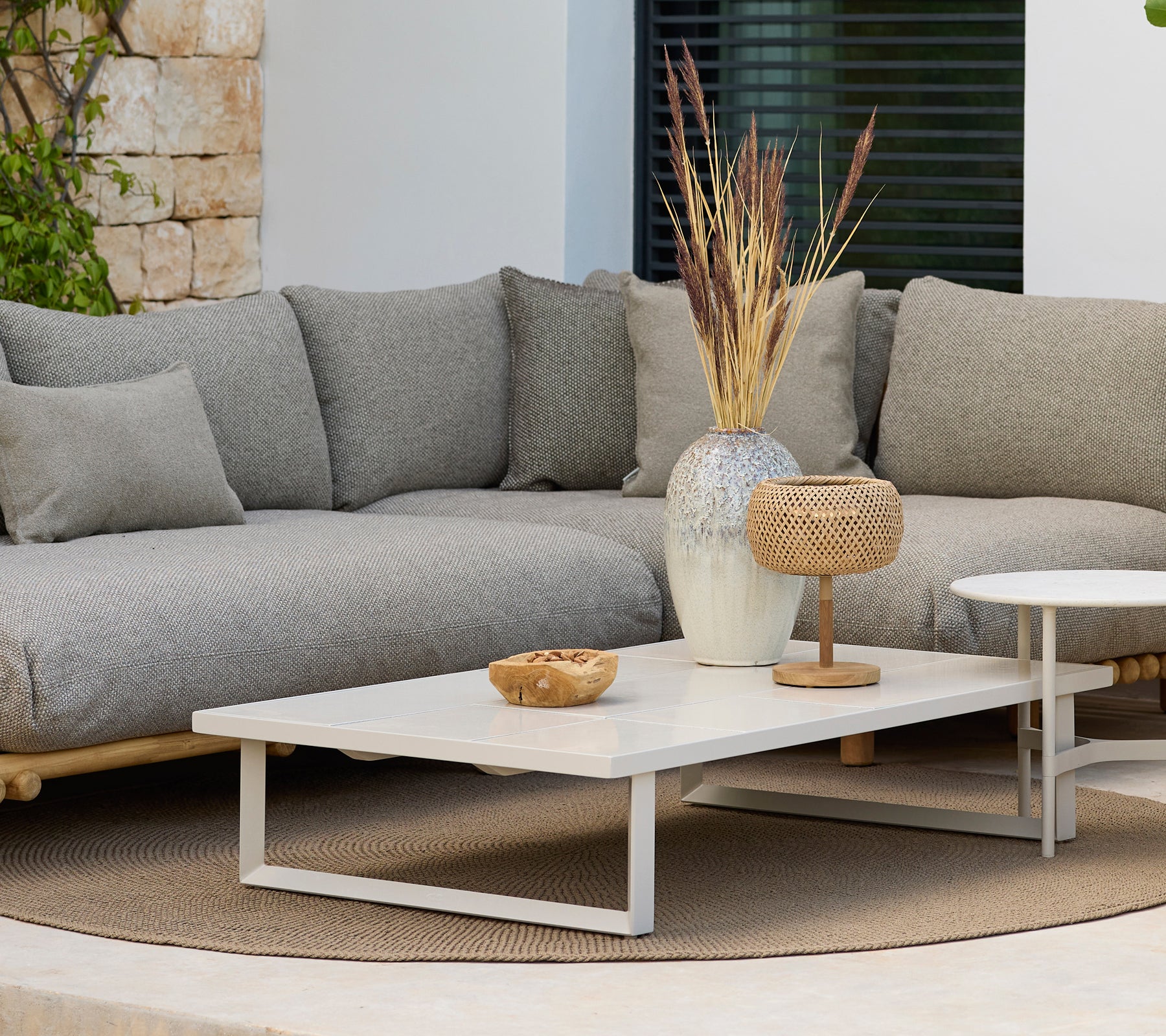 Moderne loungeområde med en grå sofa og et hvitt kaffebord med dekor.