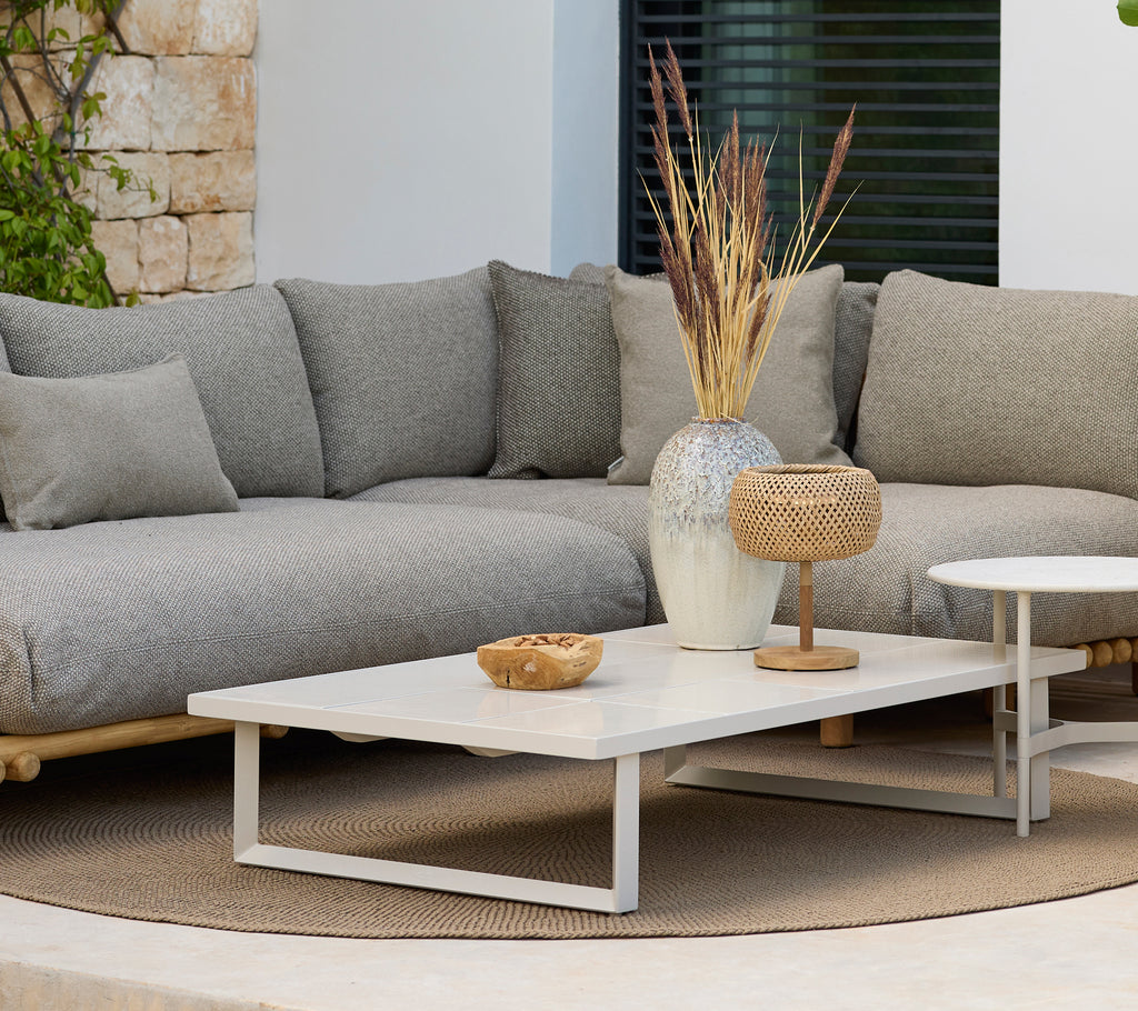 Moderne loungeområde med en grå sofa og et hvitt kaffebord med dekor.