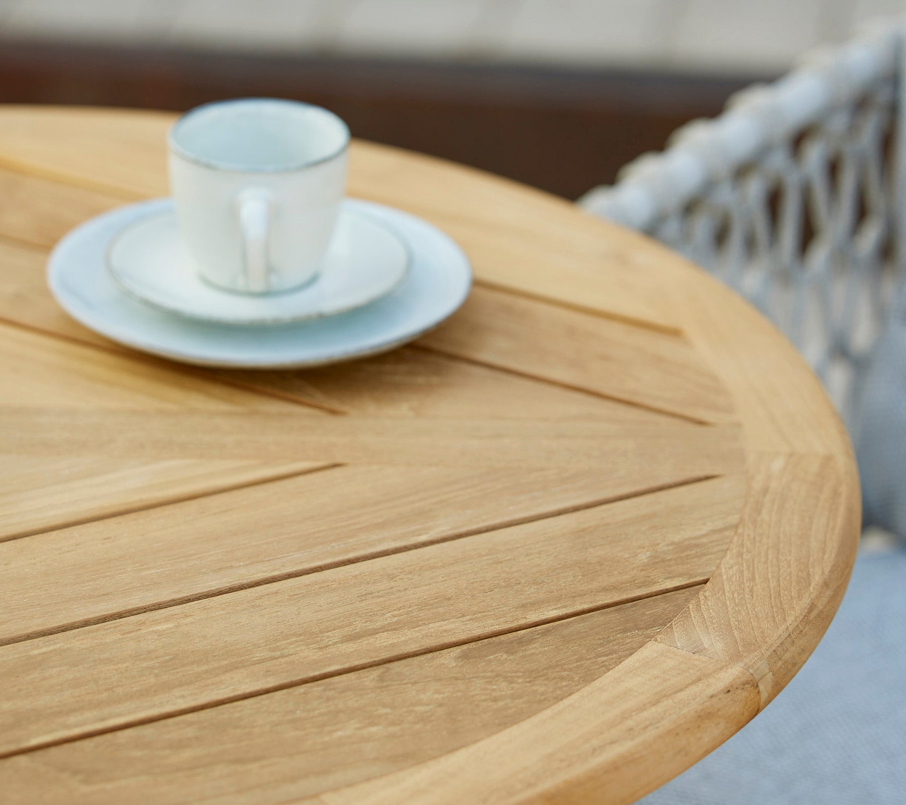 Et trebord med en kaffekopp og tallerken oppå, som viser en minimalistisk og innbydende kaféinnstilling.