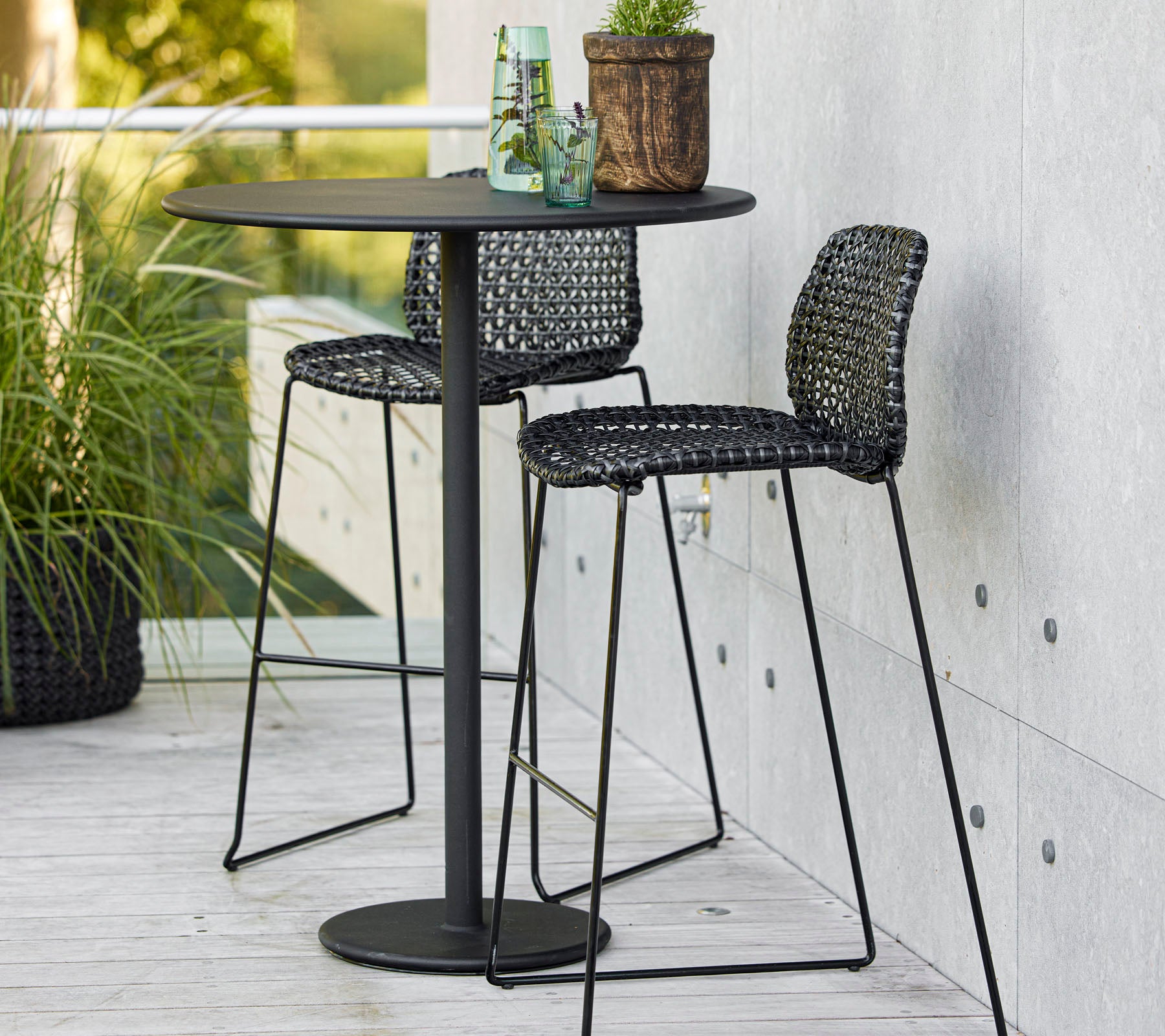 Stilig bar-set med et rundt bord og to vevde barstoler, perfekt for å skape en livlig sosial atmosfære.