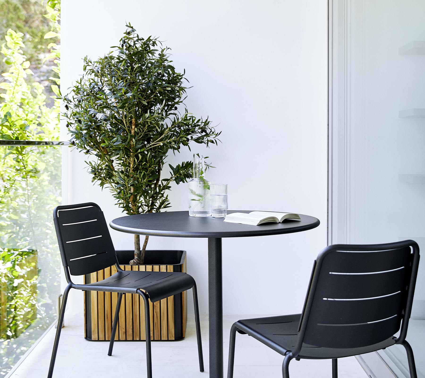 En moderne spisestue med et rundt bord, to svarte stoler og en potteplante, som skaper en stilfull og innbydende atmosfære.