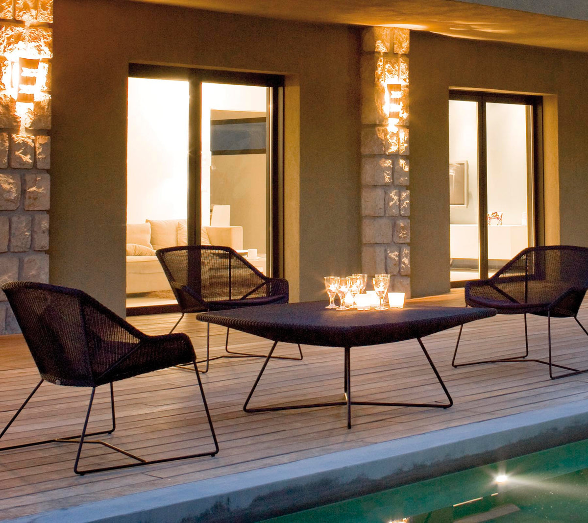 Et stilrent lounge seating arrangert med fire svarte nettstoler rundt et elegant bord, opplyst av myk ambient belysning.