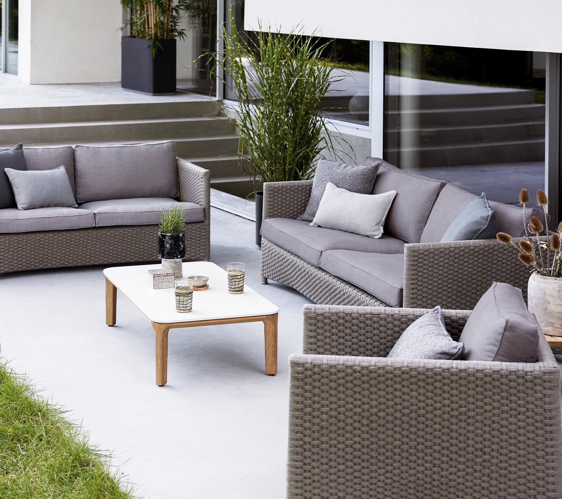 Moderne utendørs sittegruppe med en 2-seters sofa, 3-seters sofa, loungestoler og et kaffebord med dekorative gjenstander.