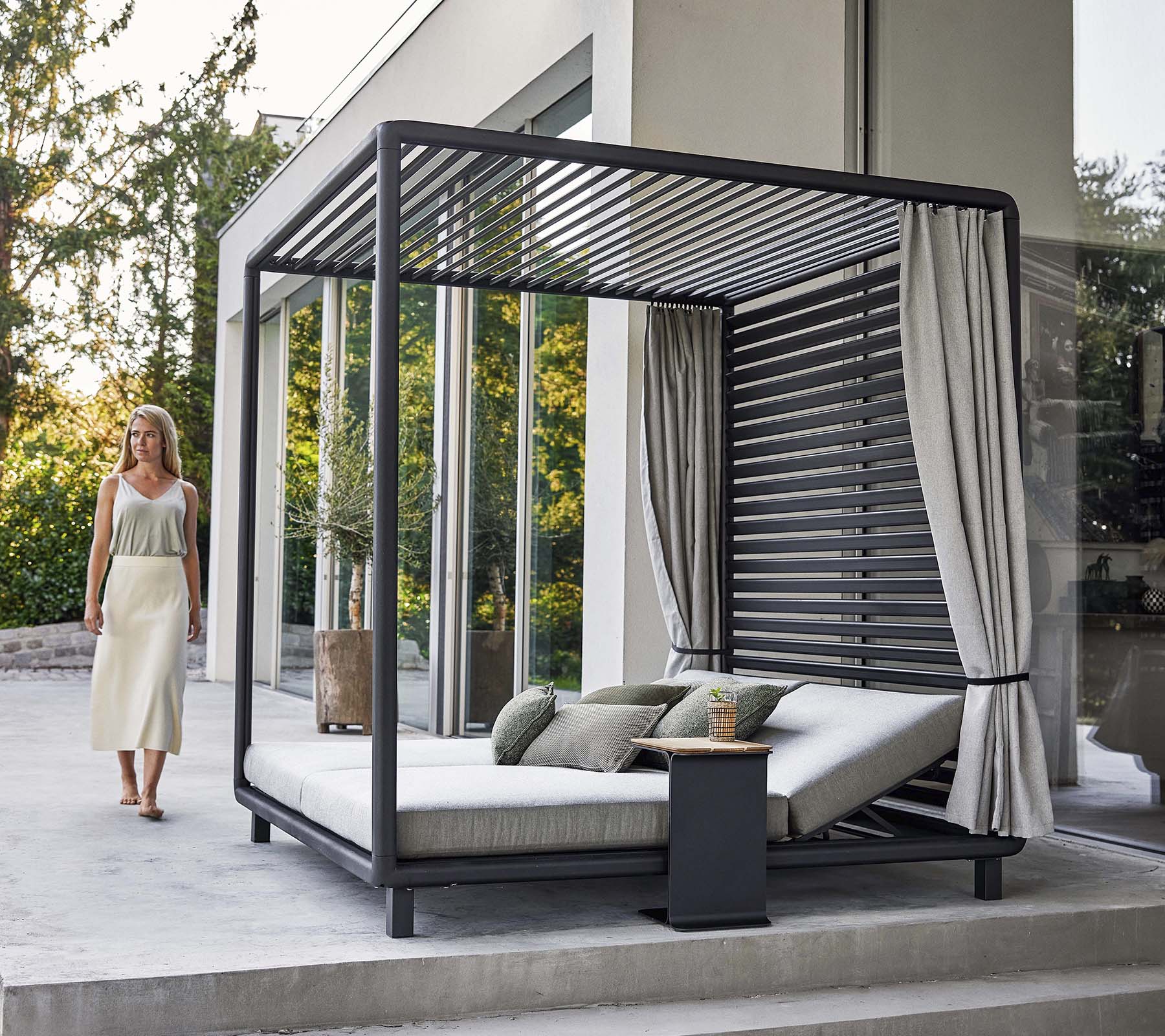 En stilig cabana med moderne design, som har et komfortabelt loungeområde og myke gardiner, plassert i en rolig omgivelse.