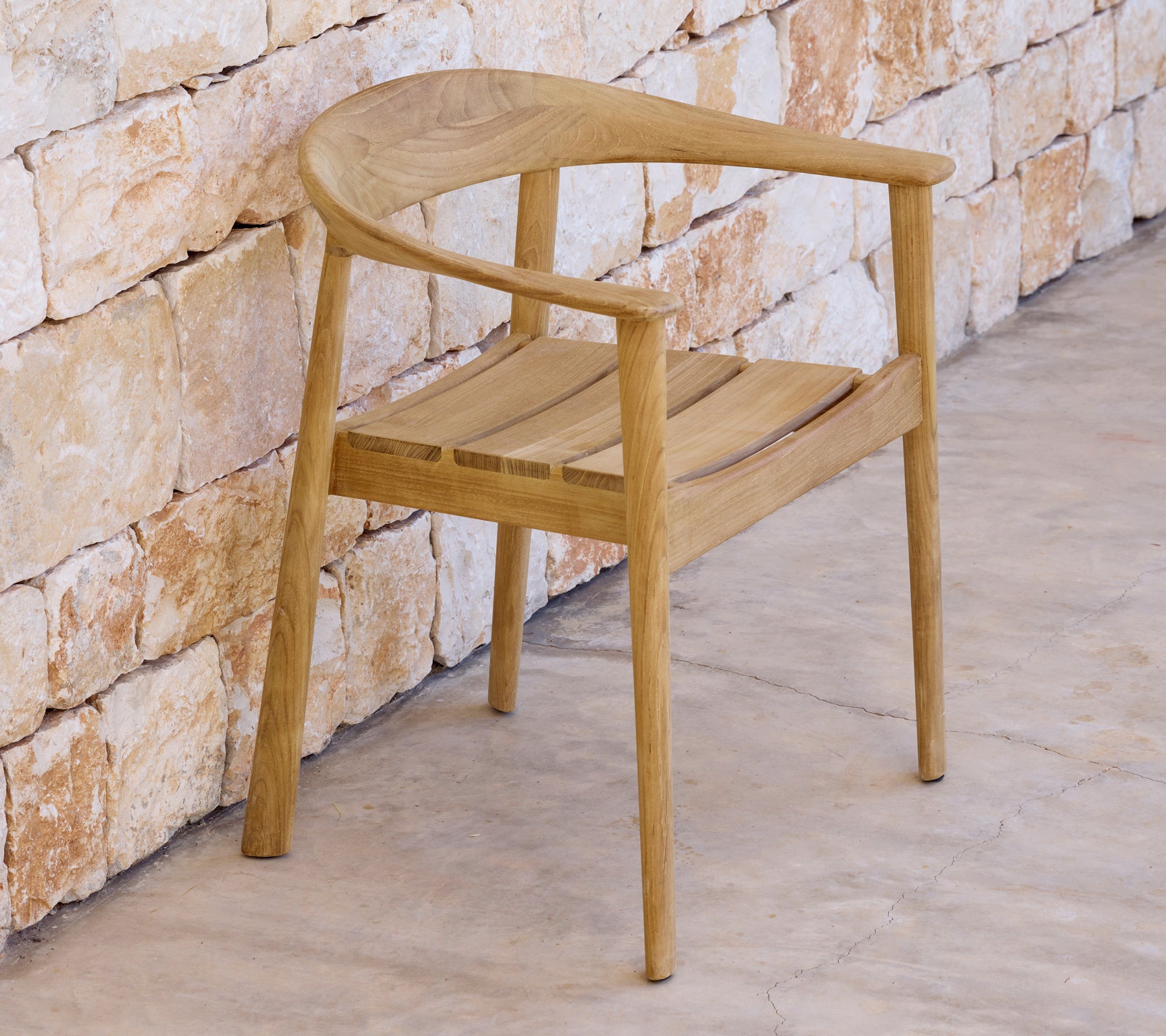 Moderne trestol ved en steinvegg i en minimalistisk setting.
