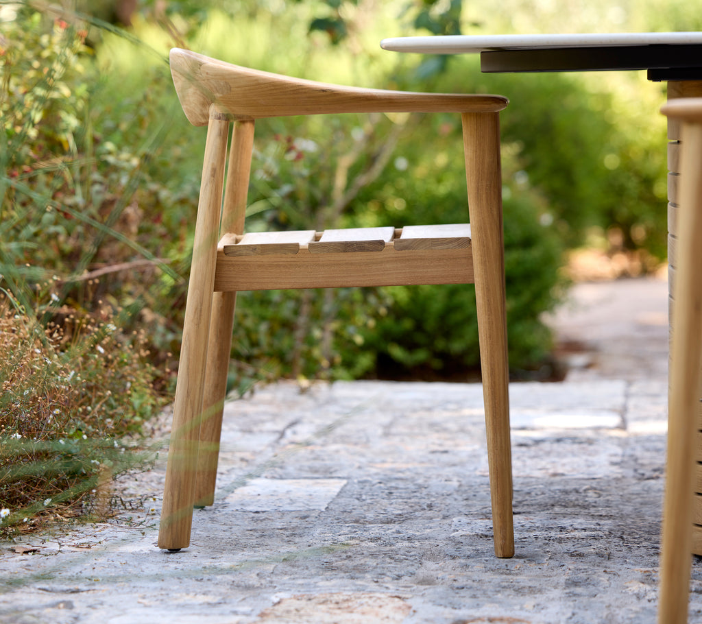 Moderne trestol ved et svart bord i en utendørs setting.