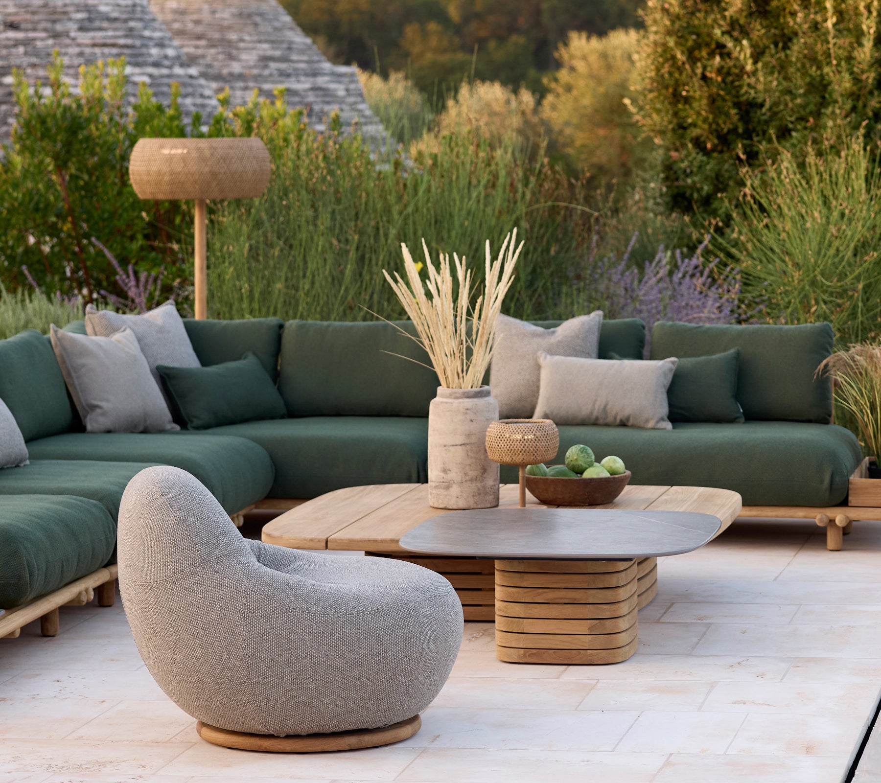 Moderne loungeområde med en grønn sofa, grå stol og rundt sofabord.