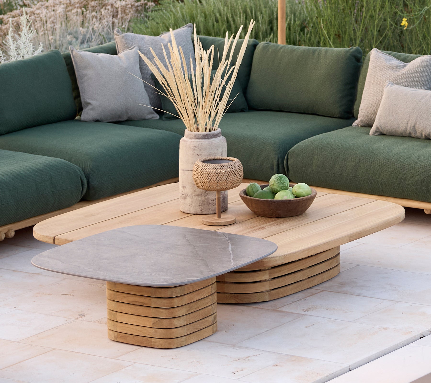 Moderne loungeområde med en grønn sofa med puter, et trebord og dekorative gjenstander.