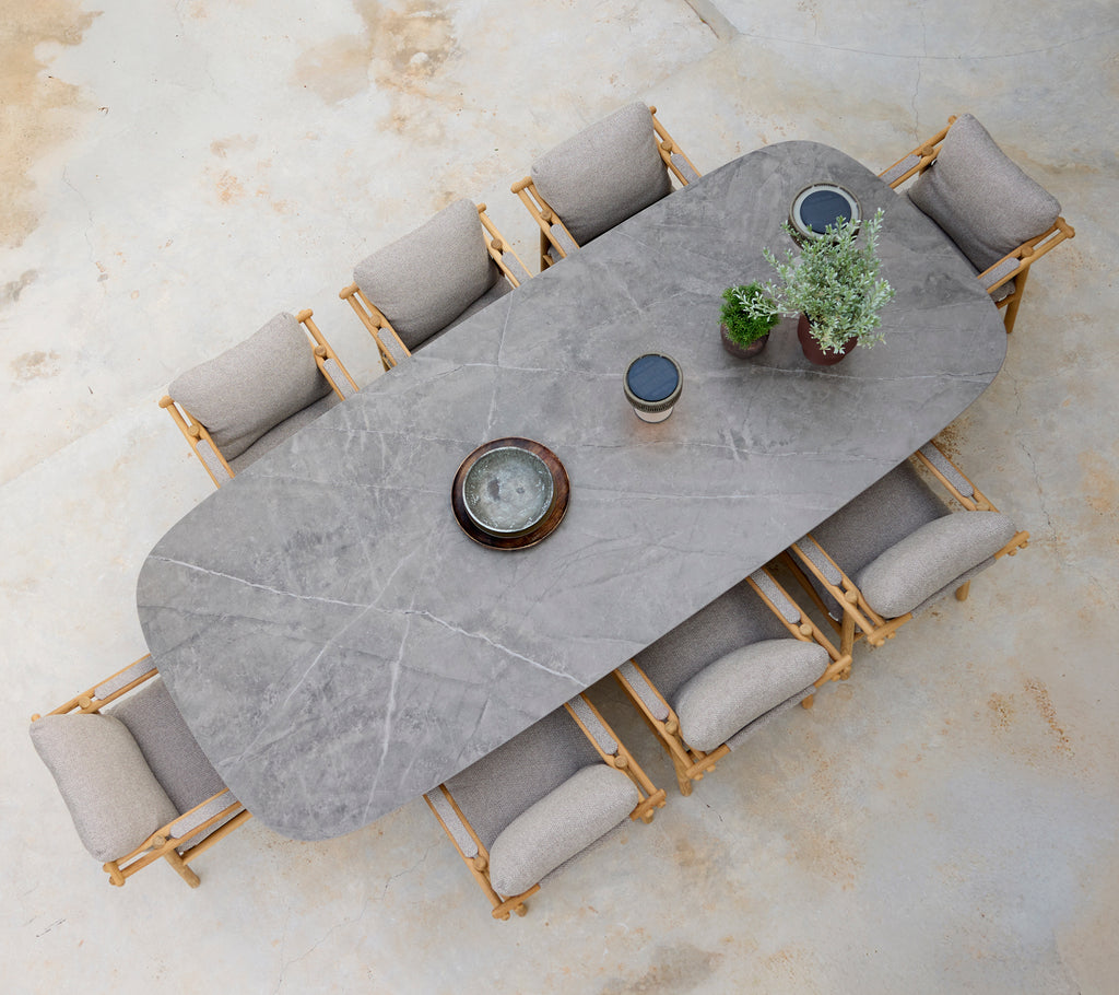 Moderne spiseoppsett med et grått bord, beige puter og stoler i tre.