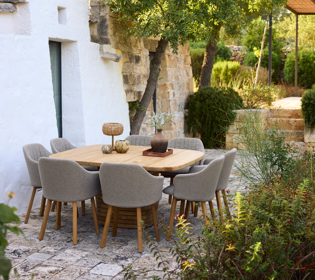 Moderne spisebord i tre omringet av grå stoler i en hageinnstilling.