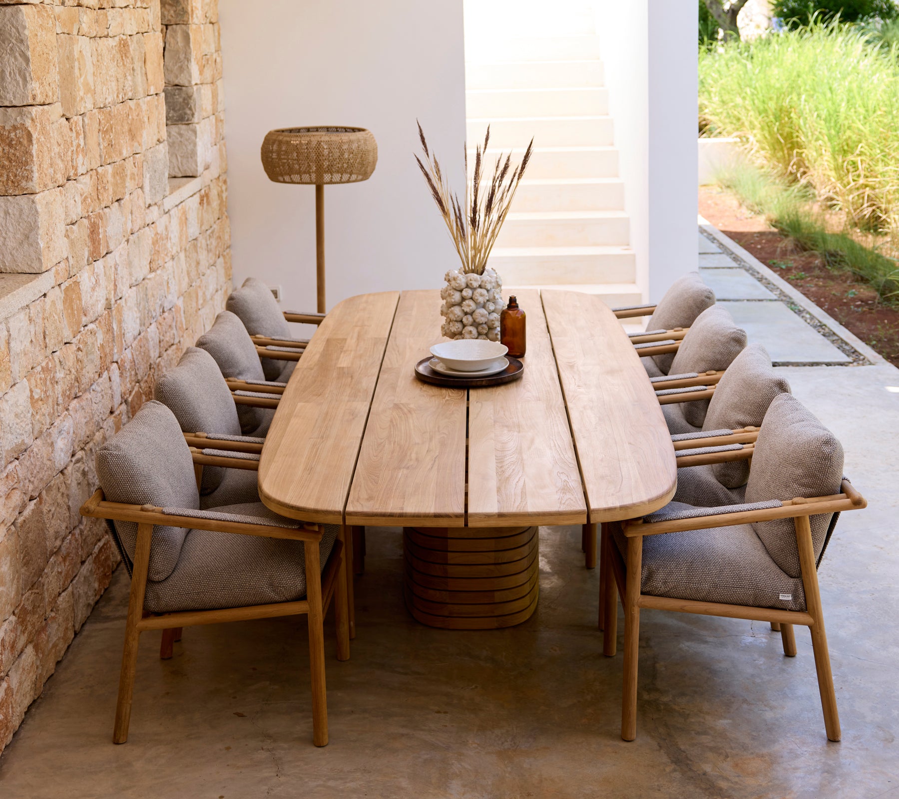 Moderne spiseoppsett med tremøbel, grå puter og trestoler.