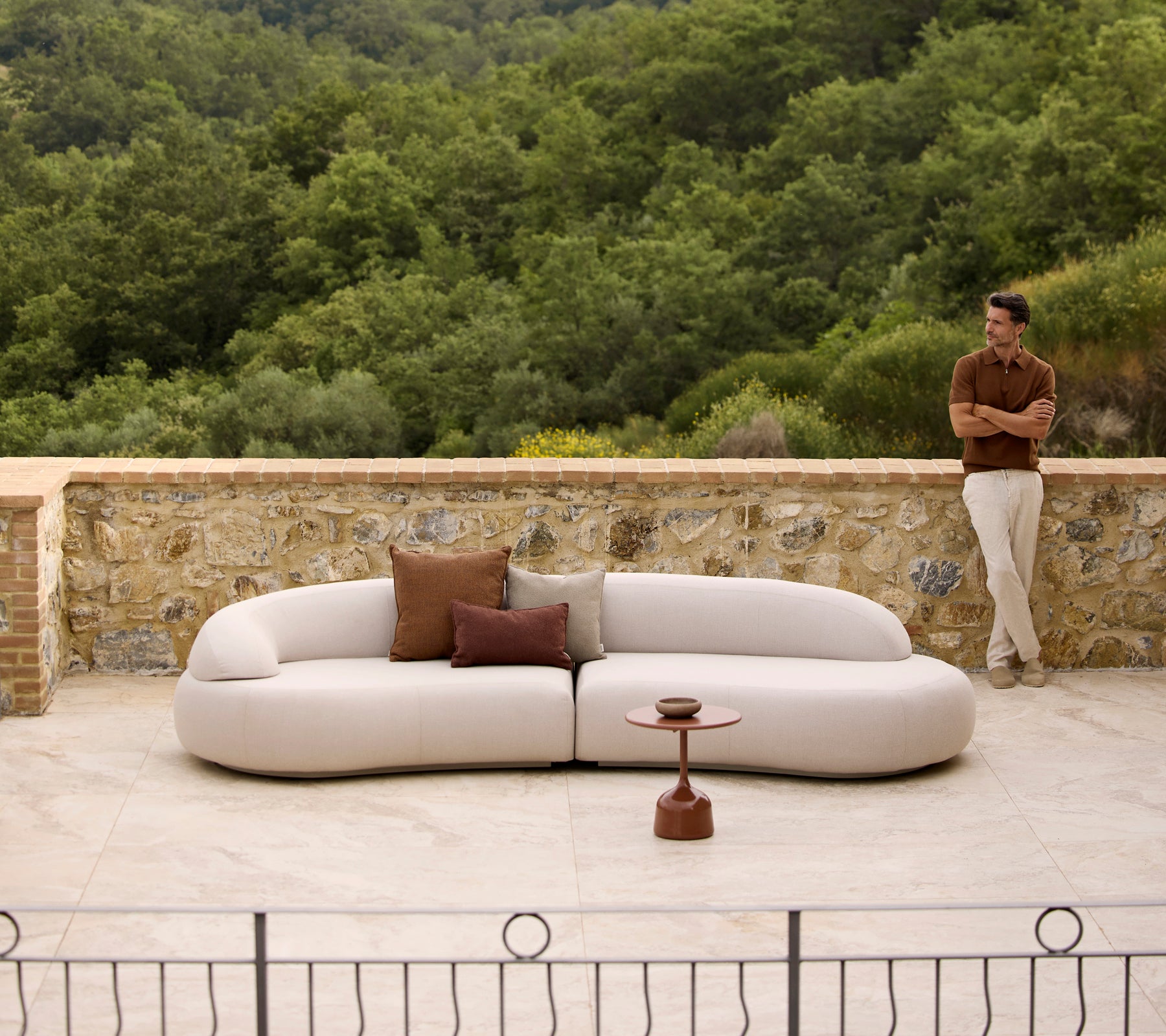 Mellow lounge-sofa med Rise puter og et Glaze-sofabord, satt mot en frodig grønn bakgrunn.