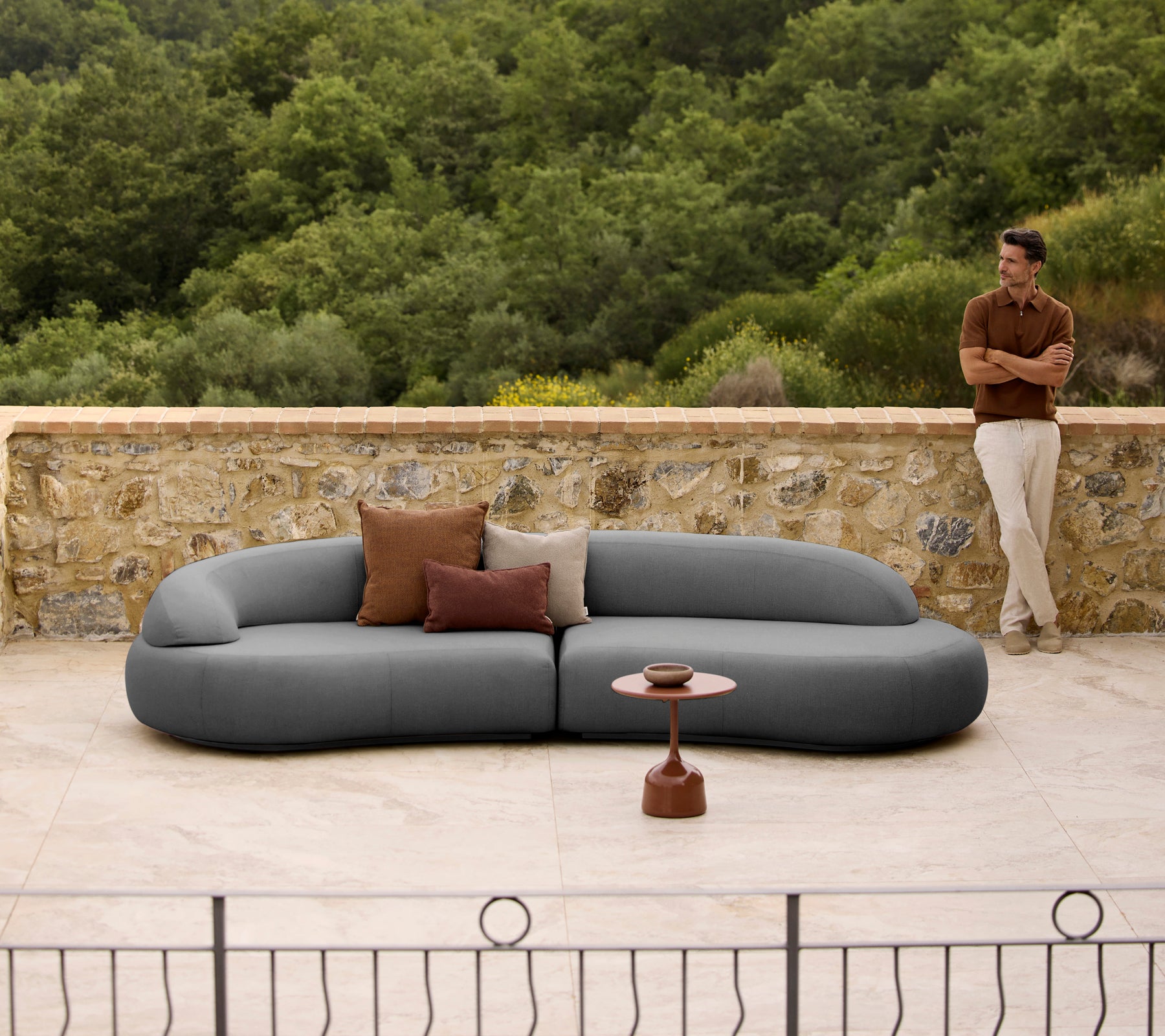 Mellow lounge-sofa med puter ved siden av et stilig Glaze kaffebord, satt mot en naturlig bakgrunn.
