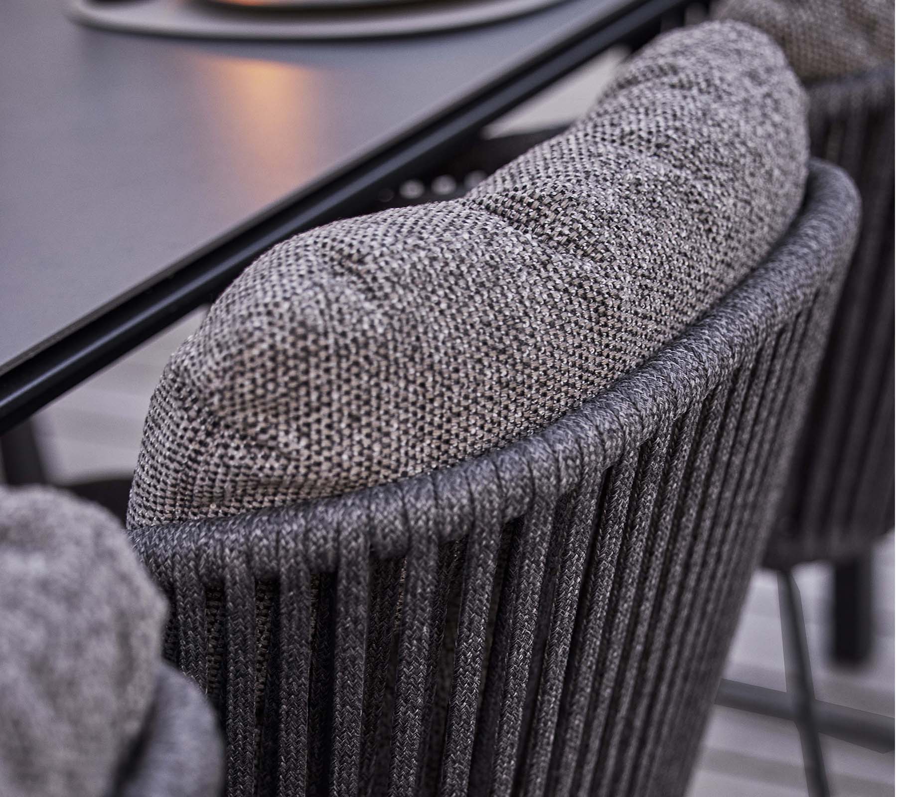 Nærbilde av en teksturert stolerygg med en myk, polstret pute, med et stilig vertikalt ribbet design.