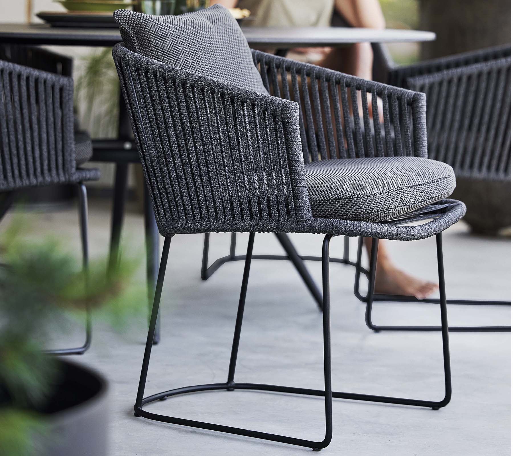 Stilig stol med et vevd design og mykpute, støttet av en slank metallramme, perfekt for moderne rom.