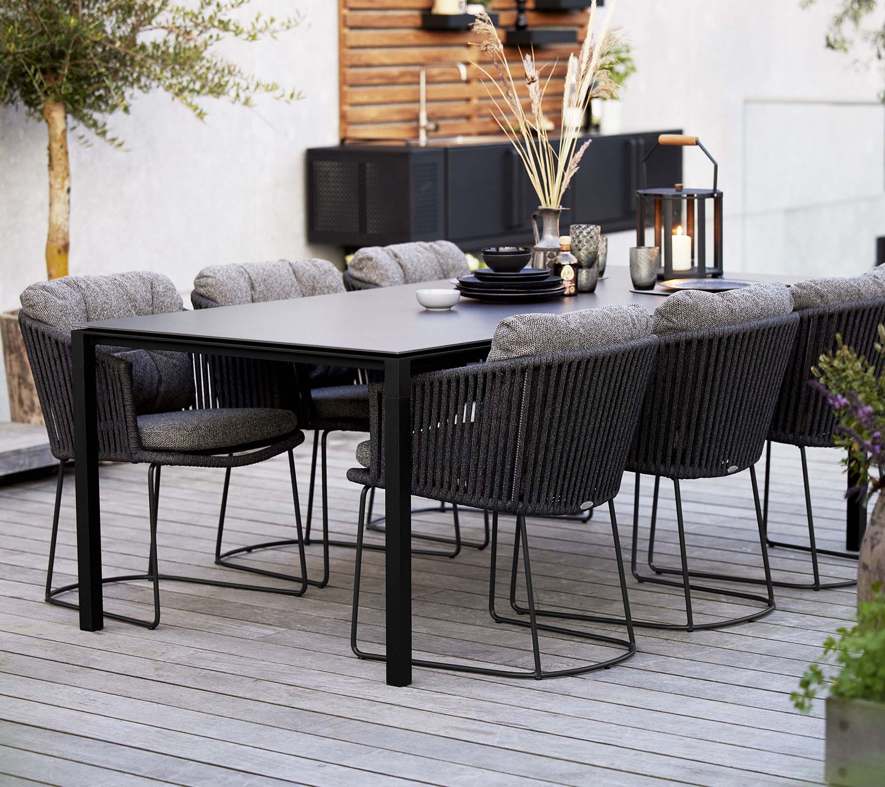 Et stilfullt spiseoppsett med et elegant bord omgitt av komfortable vevde stoler, prydet med dekorative elementer og planter.