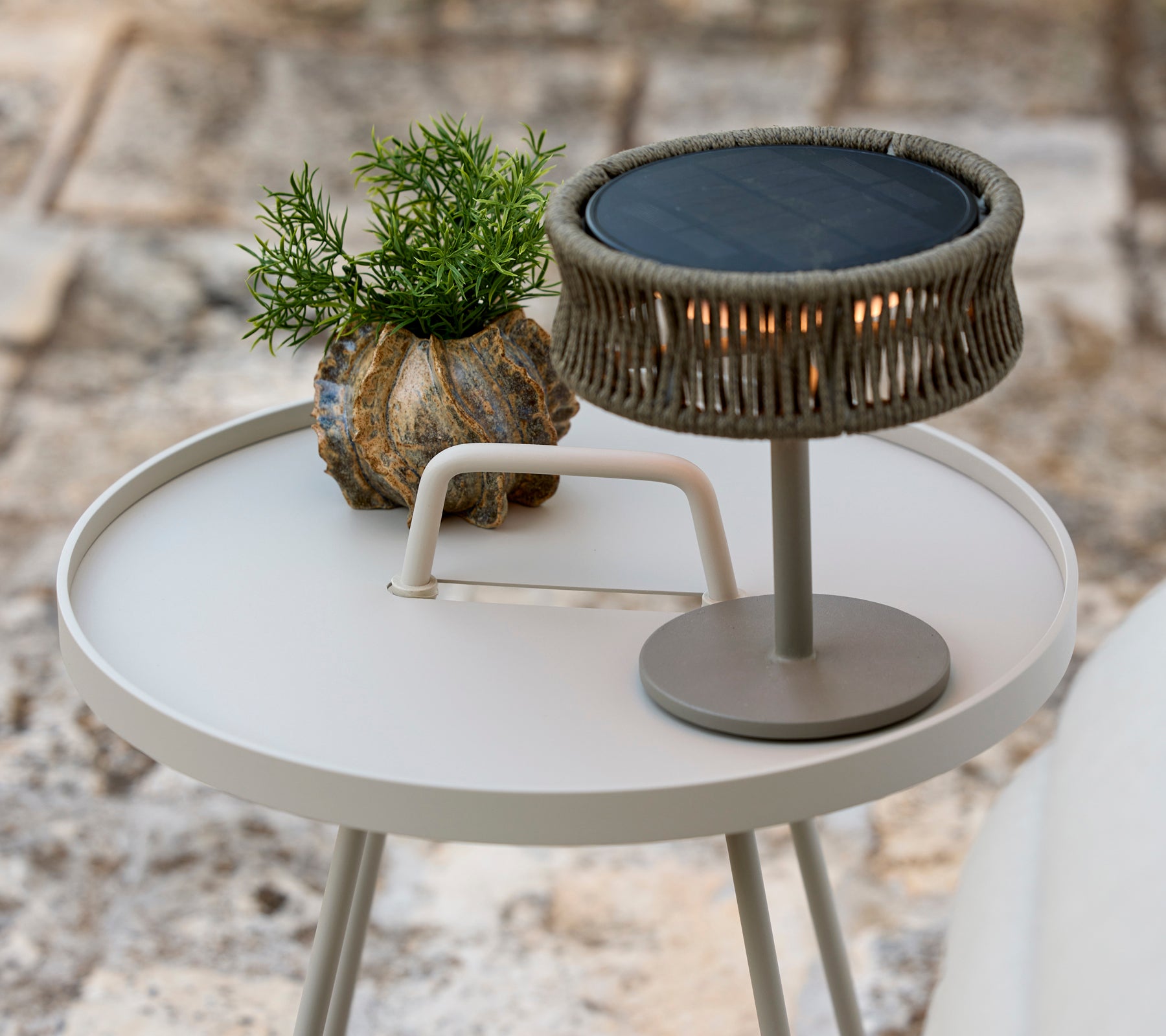 Moderne grå sidebord med en grønn plante og en stilig bordlampe.
