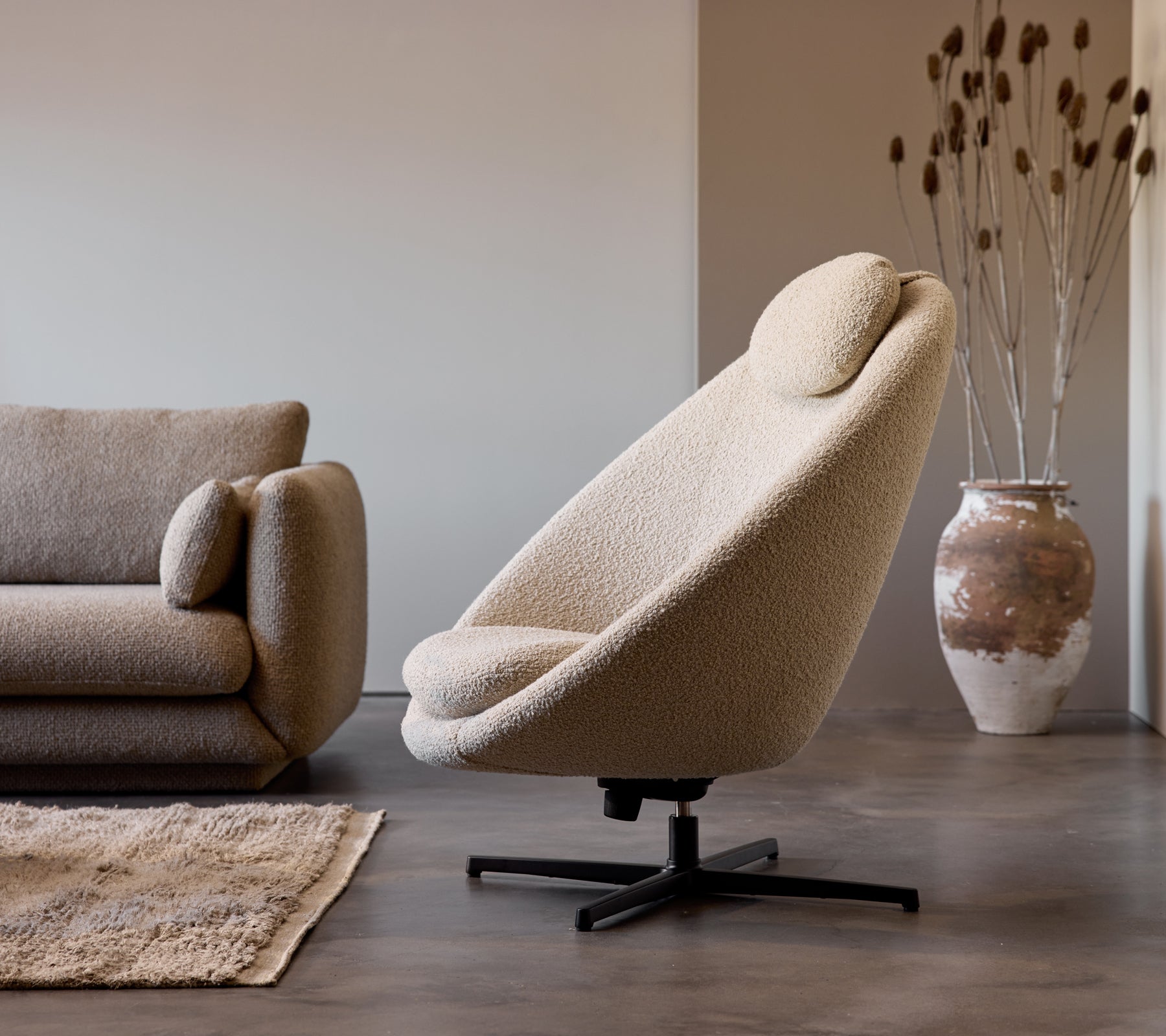 Pace stol i taupe stoff ved siden av en Bloom 3-seters sofa, komplementert av en dekorativ vase og subtil gulvtekstur.