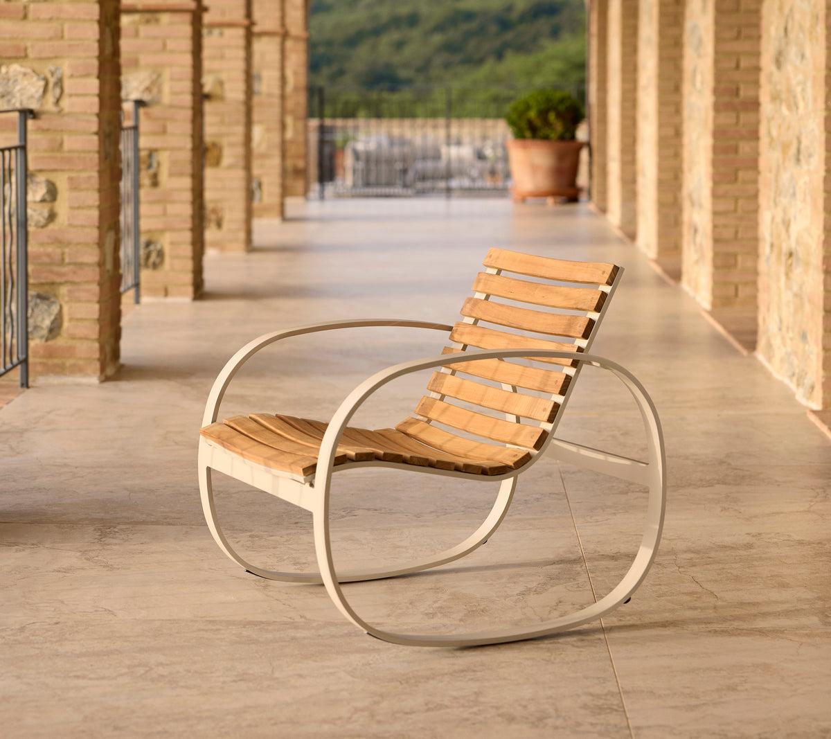 Parc gyngestol med aluminiumsramme og trelameller, plassert på en terrasse med steingulv og vakker bakgrunn.