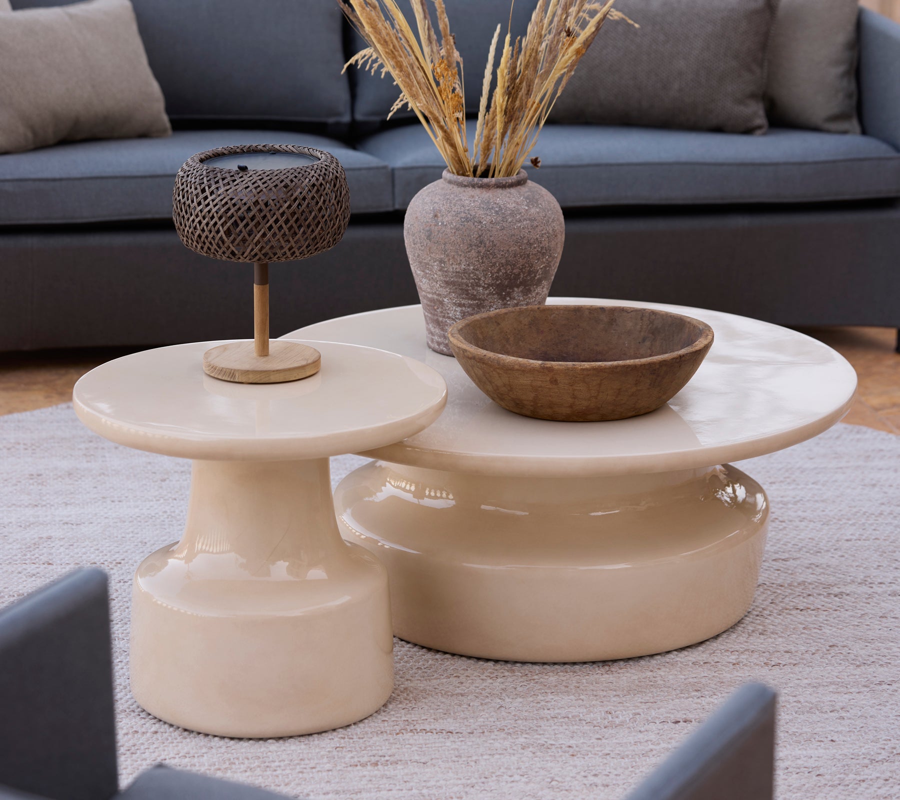 Moderne beige kaffe- og sidebord med en brun bolle og metallampe i en loungeinnstilling.