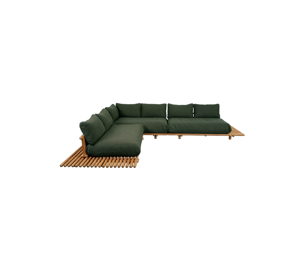 Moderne teak-sofa med mørkegrønne puter i en lounge-setting.