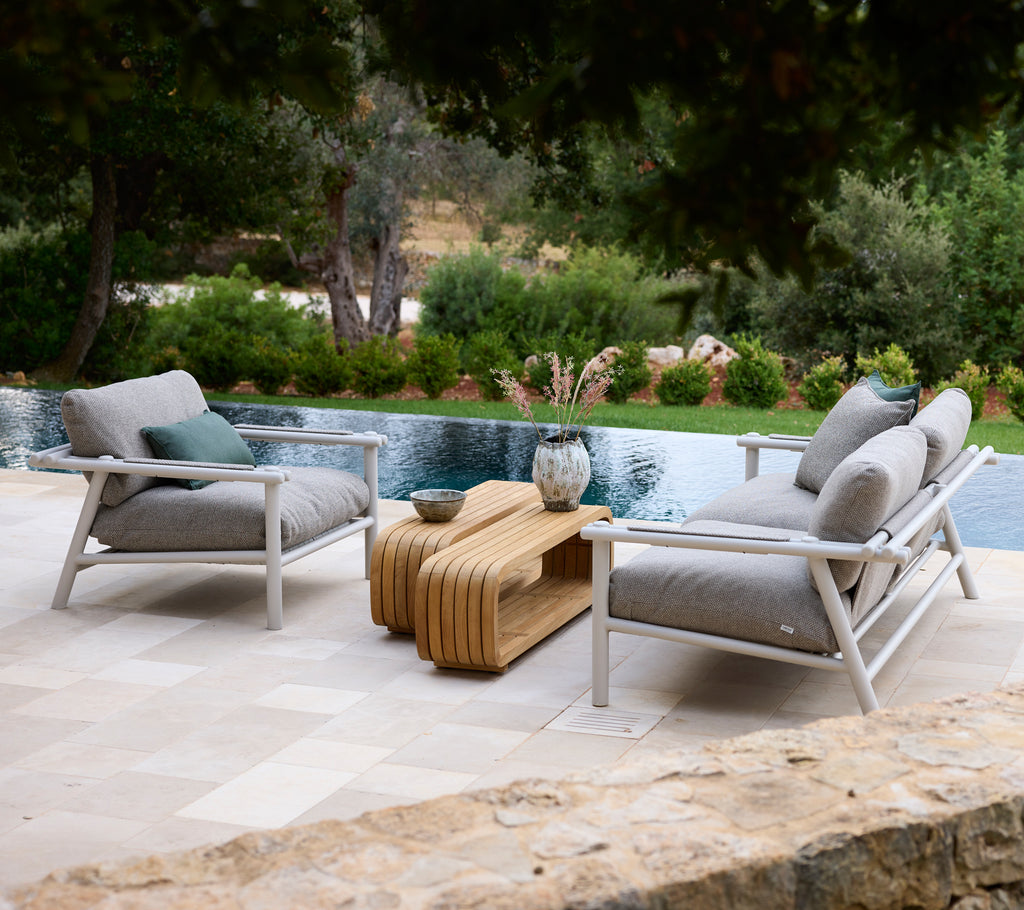 Moderne loungeområde med hvite stoler med grå puter og et tremøbel.