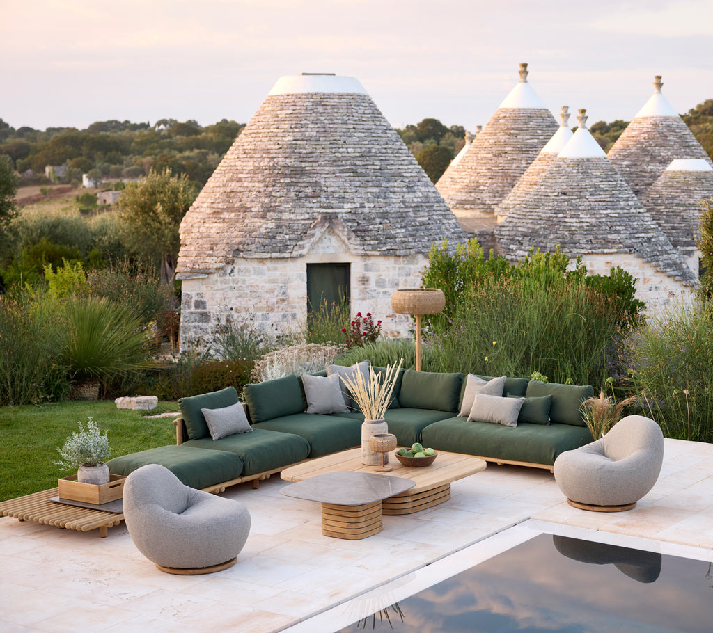 Moderne utendørs loungeområde med grønn seksjonssofa, grå lenestoler og trebord.