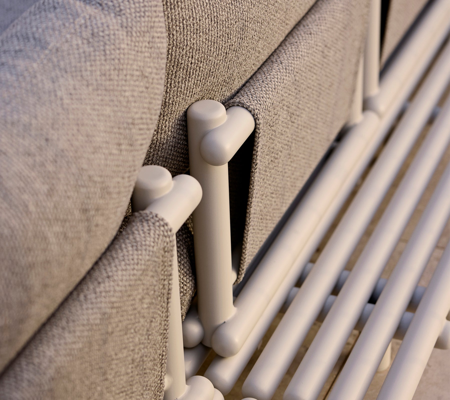 Nærbilde av en loungeplattform med aluminiumsstaver og et teksturert grått stoff, som fremhever moderne designelementer.