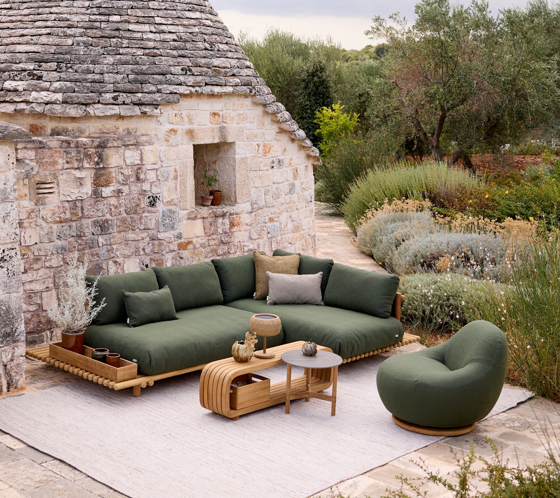 Moderne grønn sofa og stol med et brunt bord i en hageinnstilling.