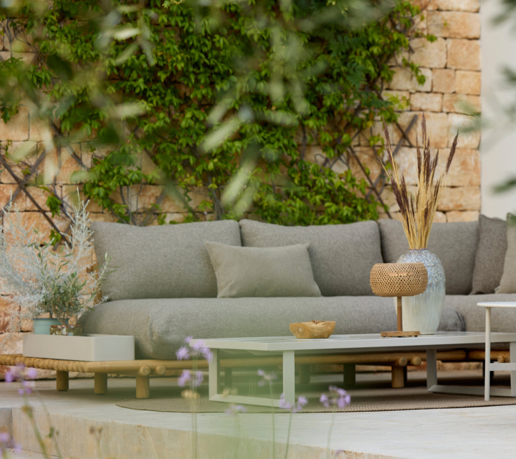 Moderne grå sofa med et trebord i et stilfullt uterom.