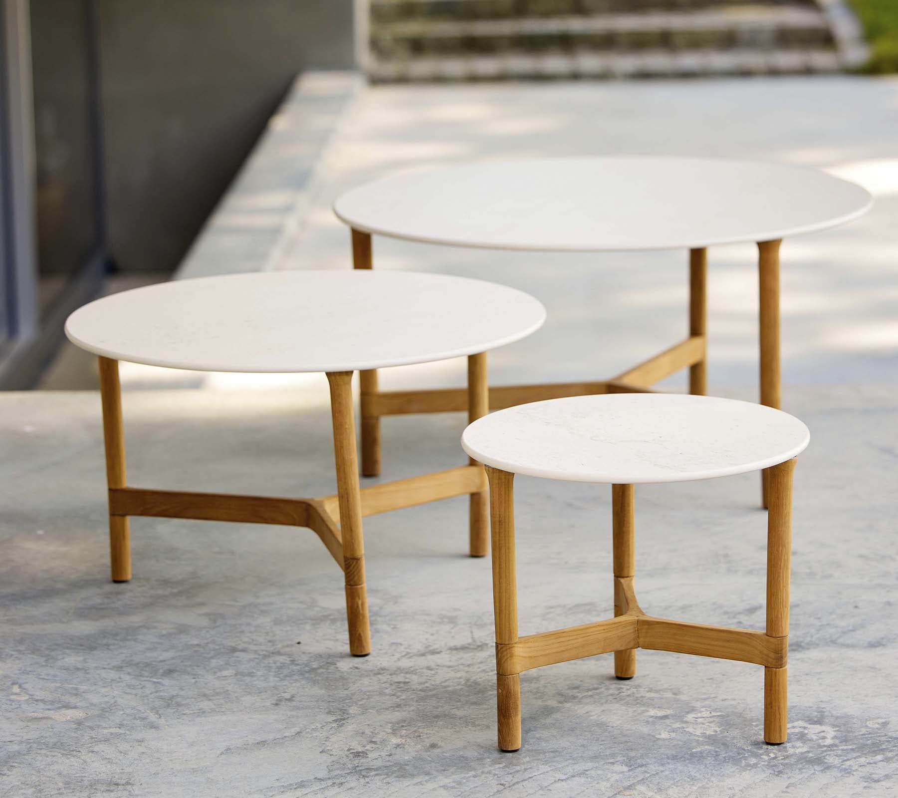 Tre moderne kaffebord i forskjellige størrelser med hvite topper og trebein, som viser et stilfullt og minimalistisk design.