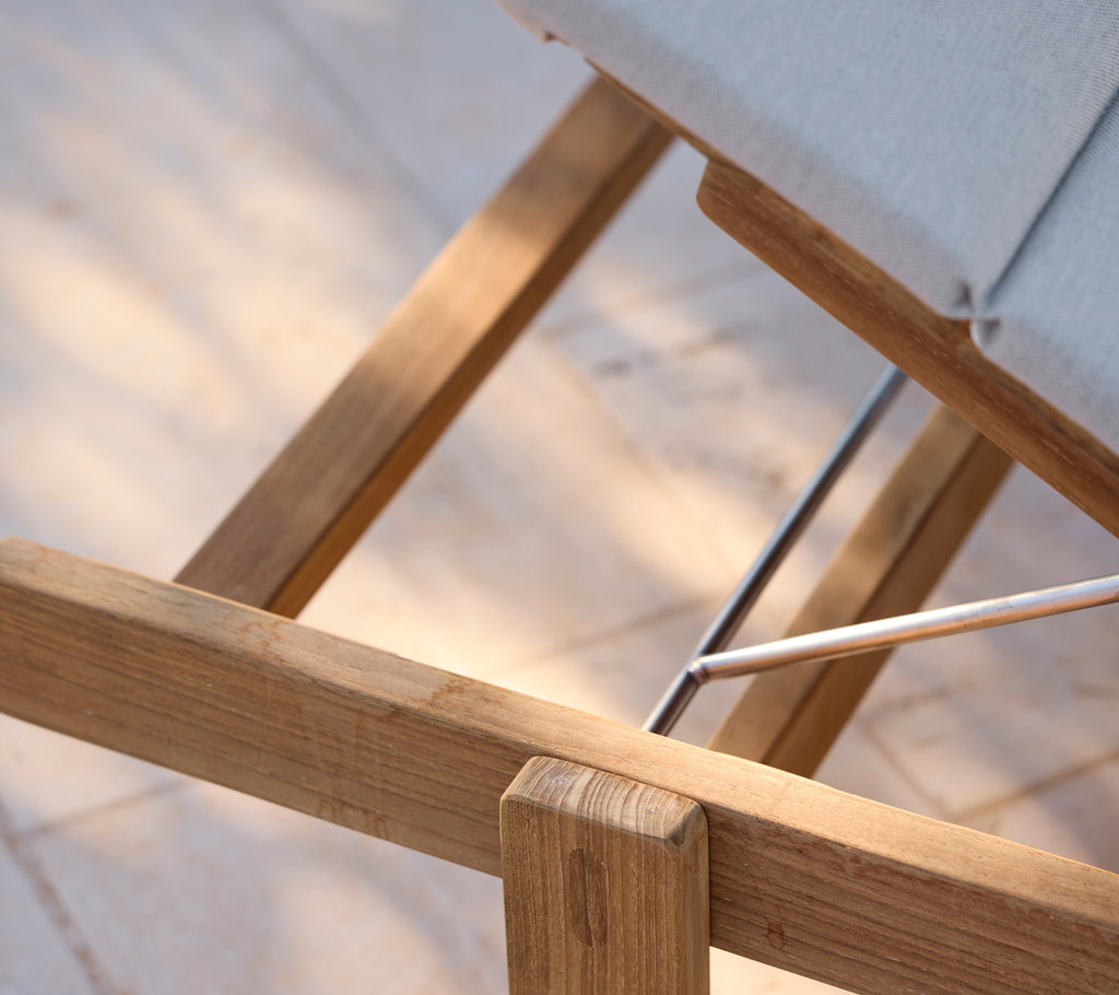 Moderne lenestol med grå pute og treramme.